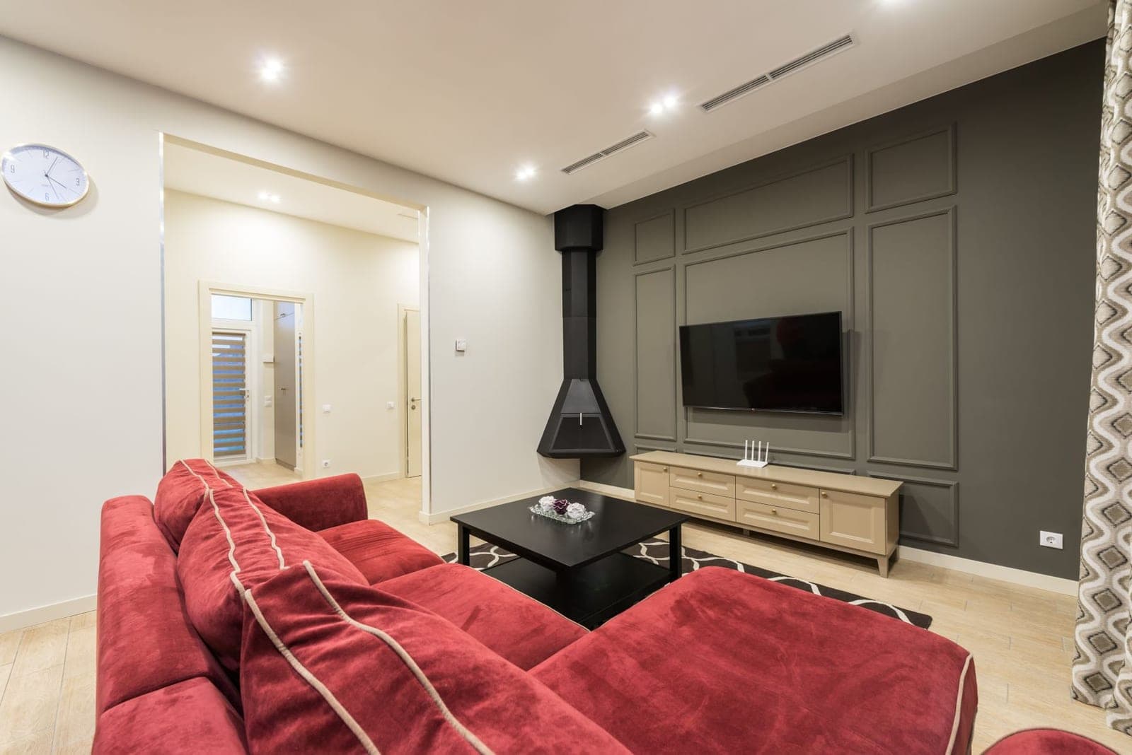 Flat-screen TV mounted centered on a dark grey paneled feature wall above a low wooden console in a living room, with no visible cables